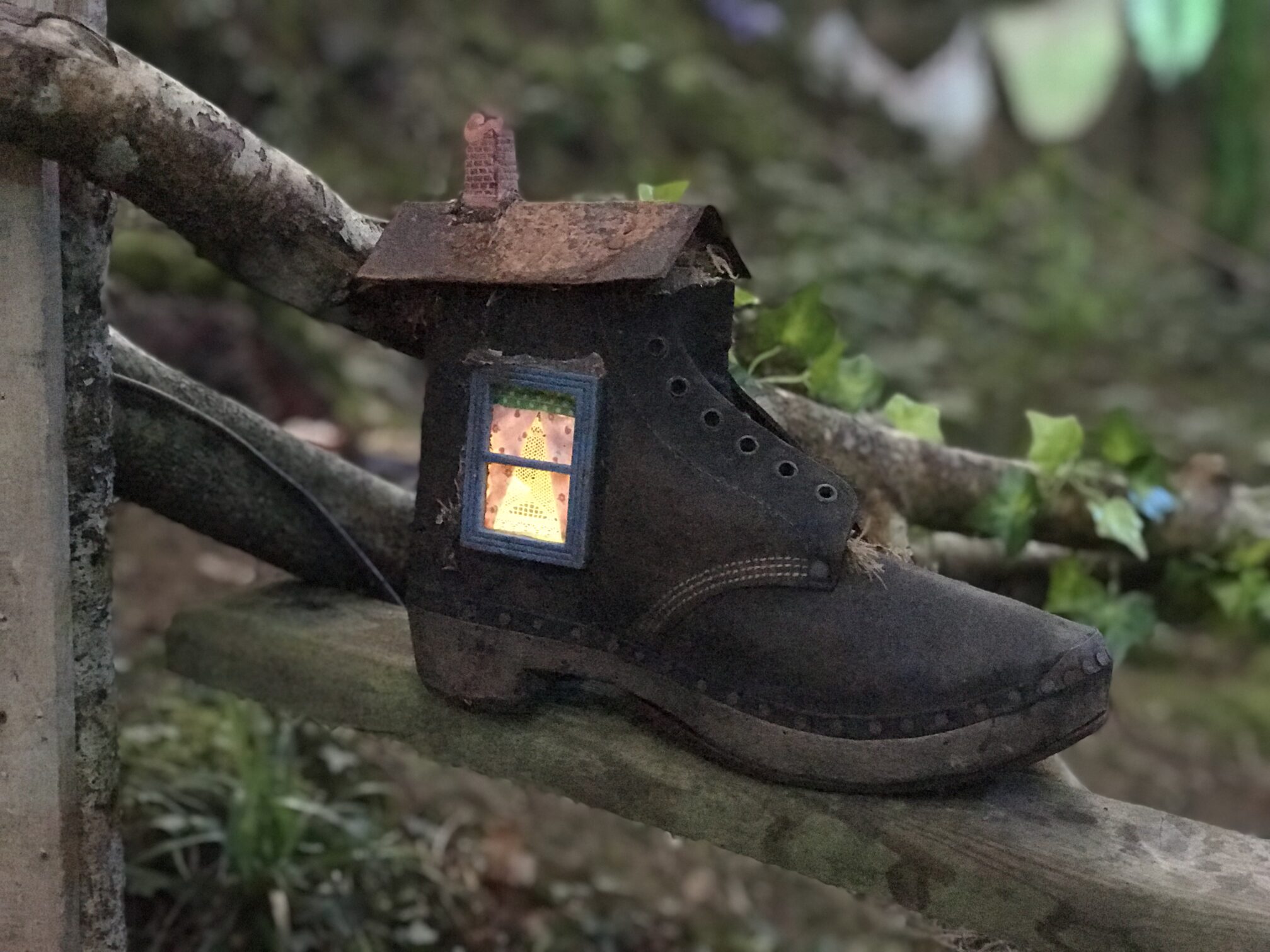 a house made out of a boot sat on a tree stump in Bluestone's enchanted forest