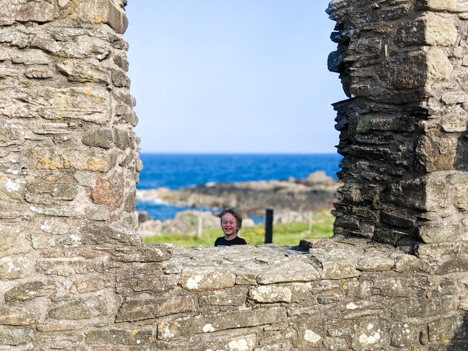 Dexter peeking through St Ninian's Chapel window with the sea behind him